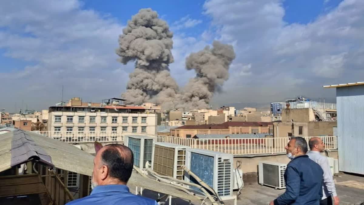 People watch as smoke rises on the skyline after an explosion in Tehran, Iran, Saturday,