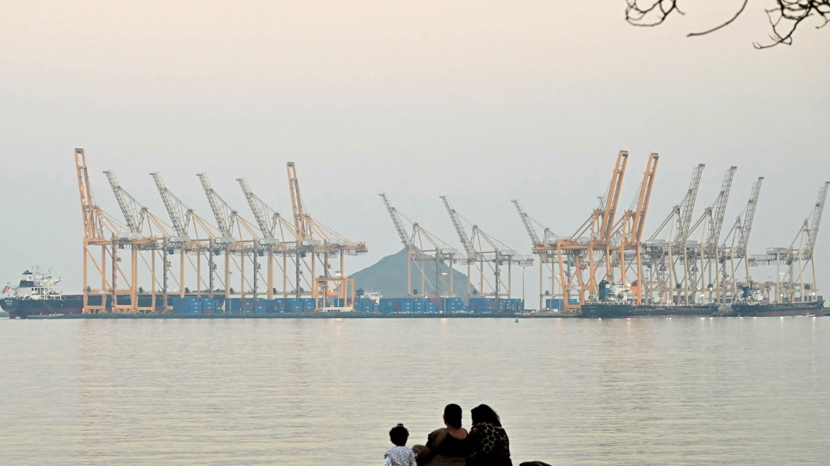 A family sits against the backdrop of a dockyard off coast city of Fujairah, in the Strait of Hormuz in the northern Emirate on February 25, 2026.