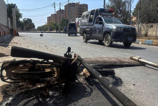 A police vehicle drives past a burnt motorcycle set on fire by angry protestors at outside the U.S. Consulate following protesters stormed the U.S. Consulate in Karachi, Pakistan, Sunday, March 1, 2026.