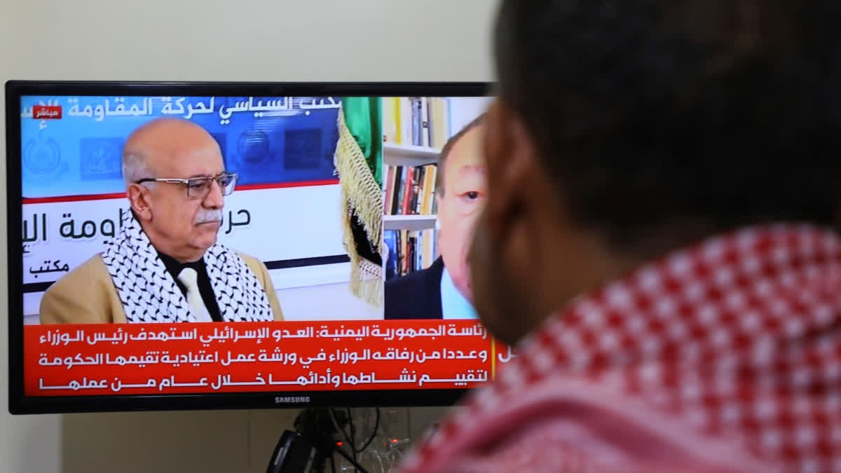 A man watches the news on TV, displaying footage of Ahmed al-Rahawi, the prime minister of the Houthi-controlled government, who was killed, along with others, in Thursday's Israeli strikes on the capital, in Sanaa, Yemen, Saturday, Aug. 30, 2025.