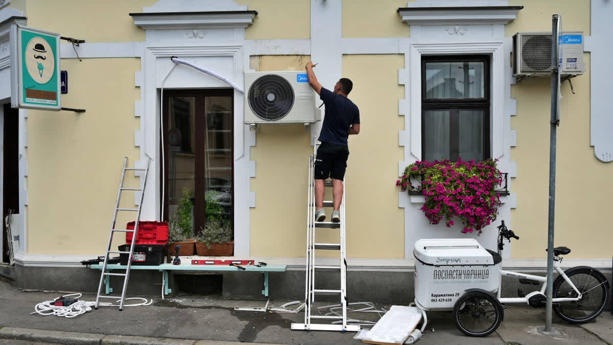 Air Conditioners Save Thousands Of Lives Yearly, But At A Cost Of Worsening Global Warming, Experts Say A worker installs a new air conditioning unit during a hot summer day in Belgrade, Serbia