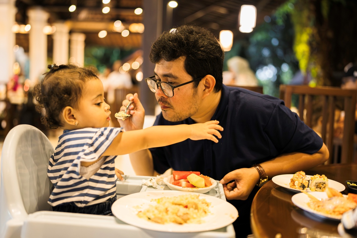 Father feeds his toddler at the table