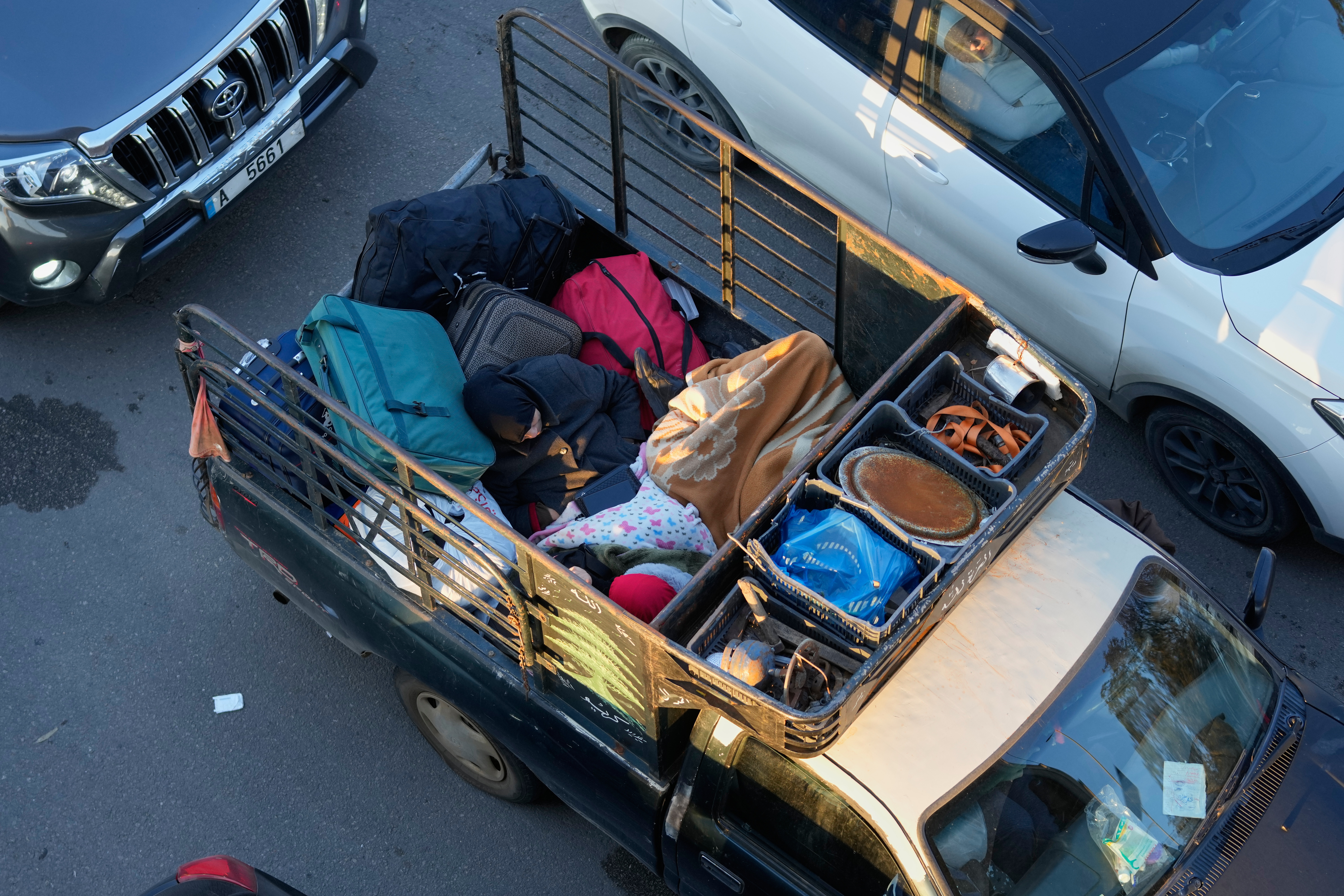A displaced woman fleeing Israeli airstrikes in southern Lebanon, sleeps between her belongings in the back of a pickup truck along a highway toward Beirut, in the southern port city of Sidon, Lebanon, Monday, March 2, 2026.