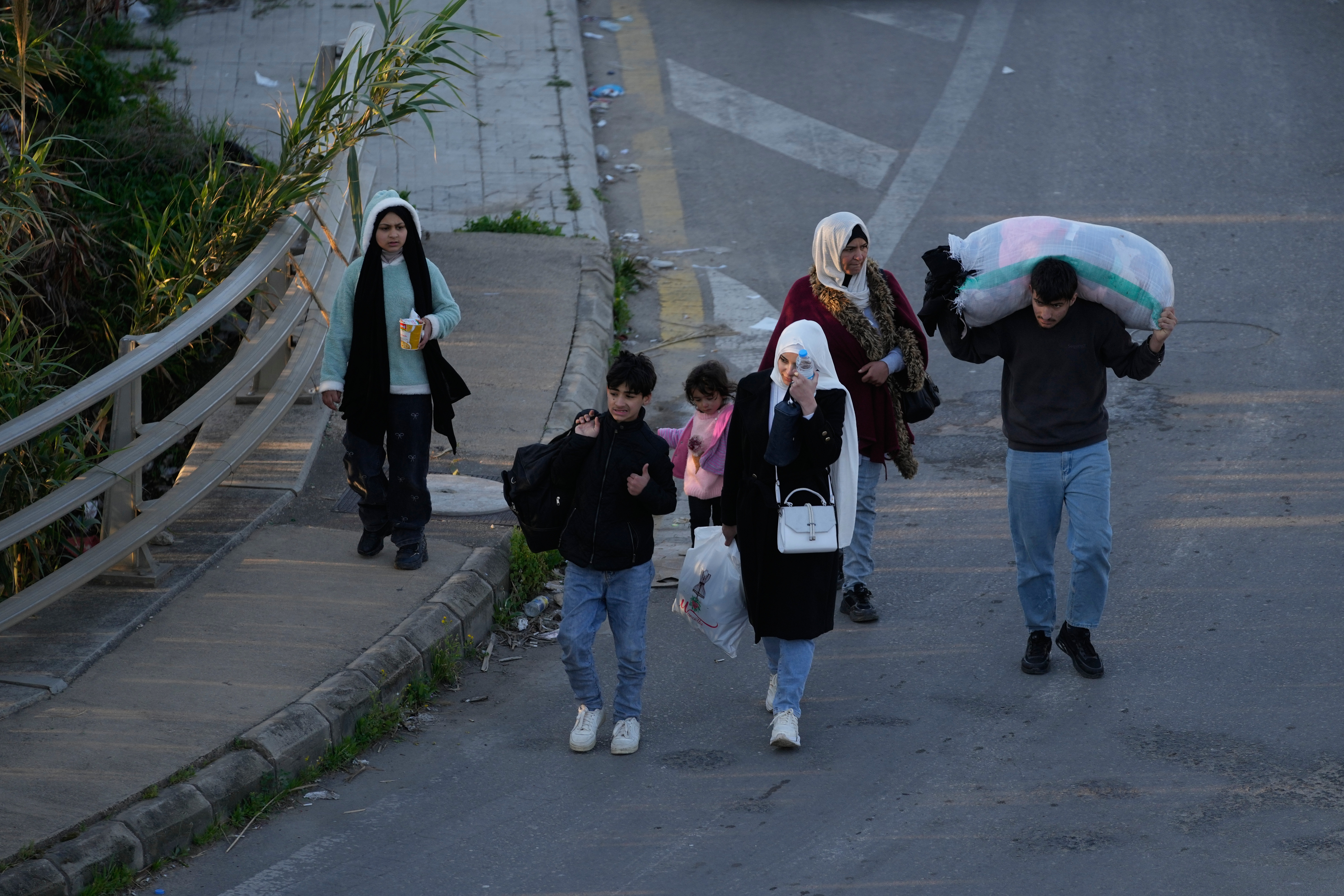 Displaced people carry their belongings fleeing Israeli strikes arrive in southern Lebanon arrive in the southern port city of Sidon, early Monday, March 2, 2026