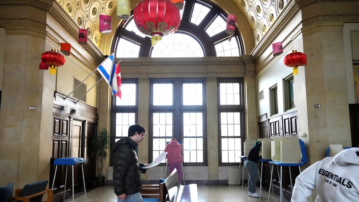Maximillian Marquez, left, walks to a voting booth at the Milwaukee Academy of Chinese Language to cast a ballot in the state's Supreme Court election, Tuesday, April 1, 2025, in Milwaukee.