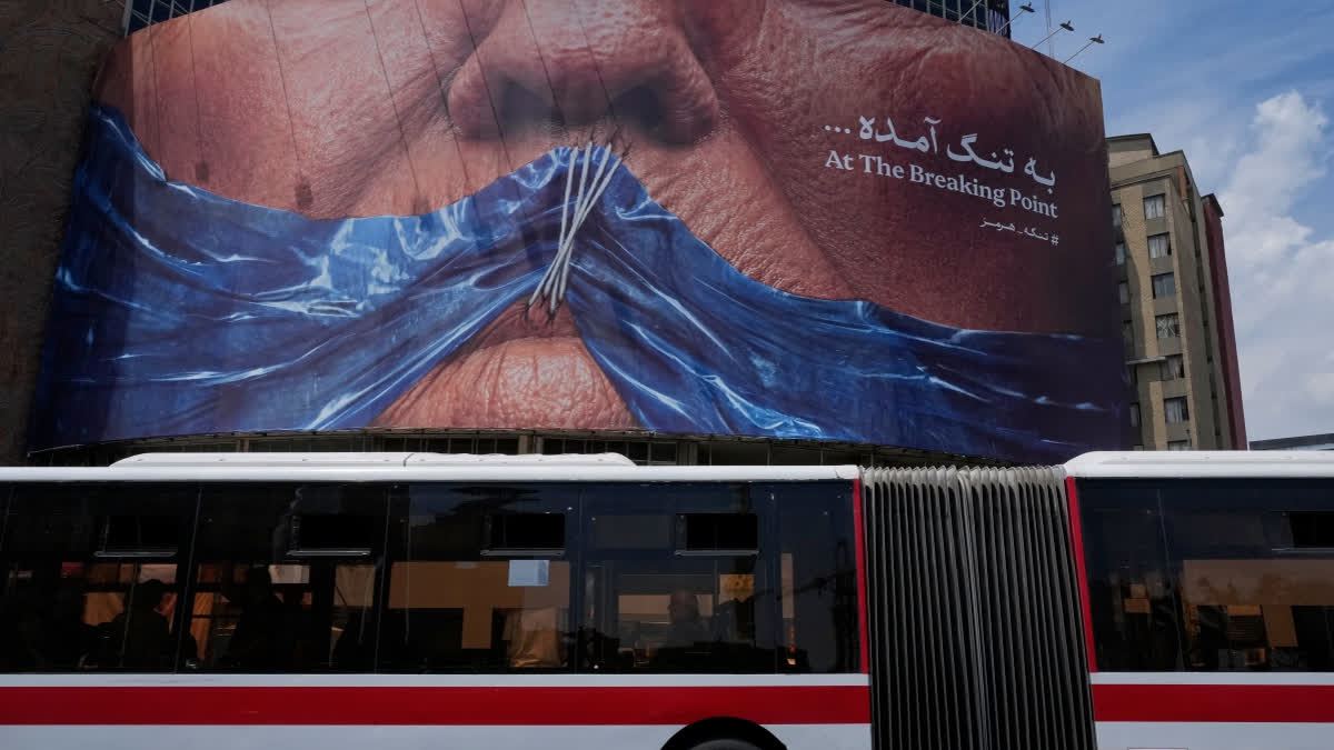 A public bus drives past a billboard with graphic showing Strait of Hormuz and sewn lips of U.S. President Donald Trump in a square in downtown Tehran, Iran, Saturday, May 2, 2026.