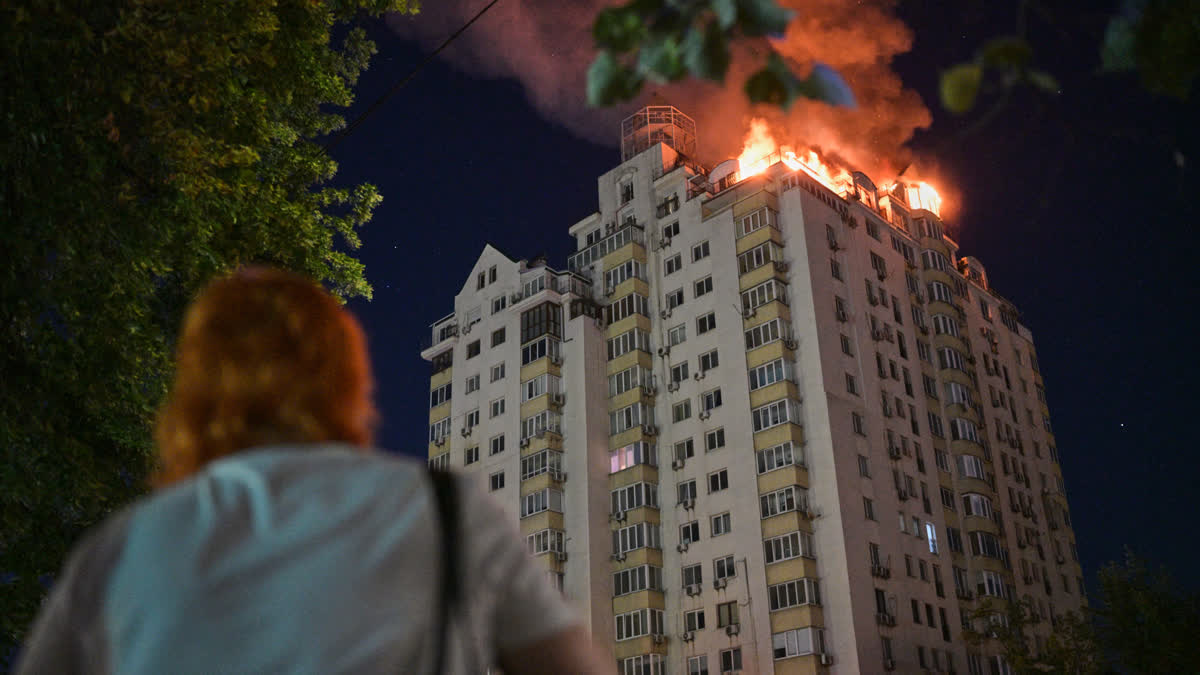 A woman looks at a burning apartment building after a Russian missile attack in Kyiv, Ukraine.