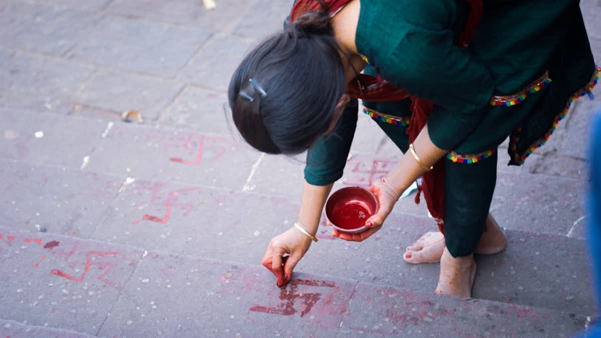 Why Do Houses Have Swastik Symbols Near The Entrance? Woman drawing swastiks outside her home