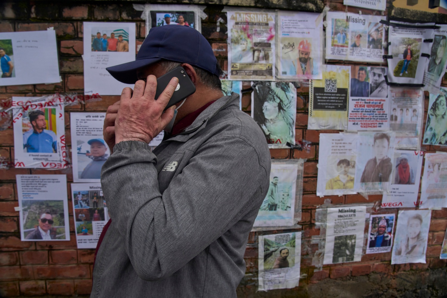 A man talks on his mobile phone after looking at photographs of people missing following flash floods displayed outside a government hospital in Kathmandu.