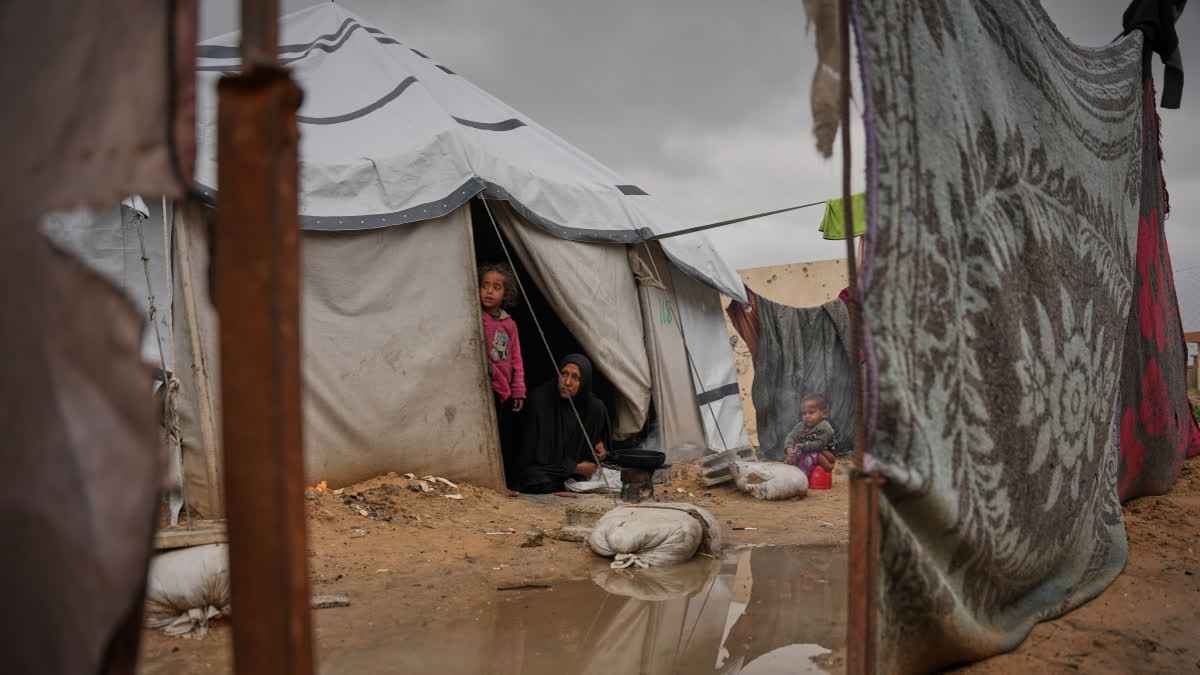 Nanaa Abu Jari cooks outside her tent after it was flooded by rainwater in Nuseirat, central Gaza Strip, Friday, Jan. 2, 2026.