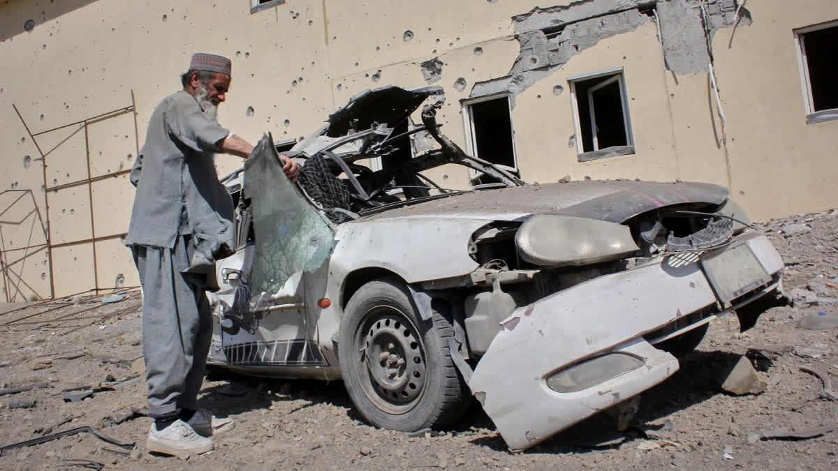 A man inspects a car damaged after a Pakistani strike in on a refugee camp in Takhta Pul district, Kandahar province, Afghanistan, Saturday, Feb. 28, 2026.