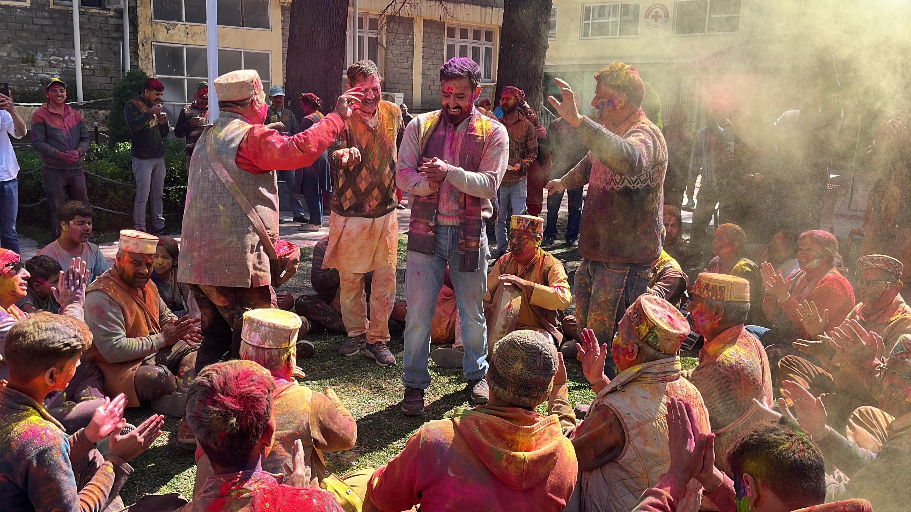 एक दूसरे को गुलाल लगाते लोग