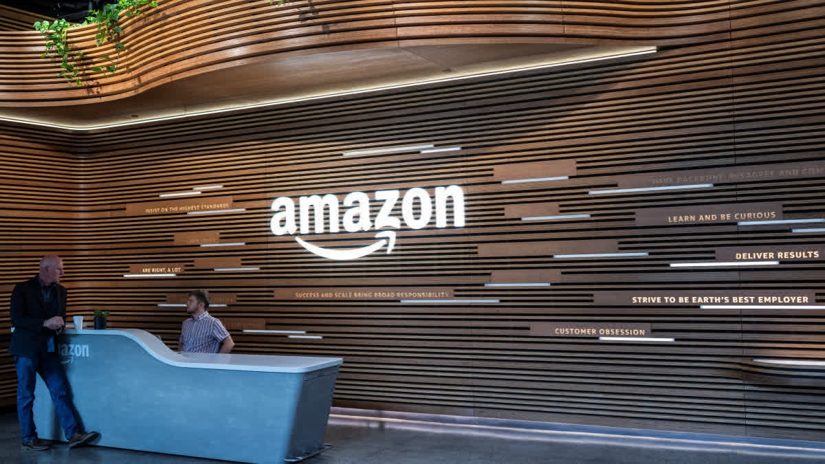 Two Amazon employees talk at one of the entrances to the new Amazon headquarters in Arlington, Virginia, on September 20, 2023.