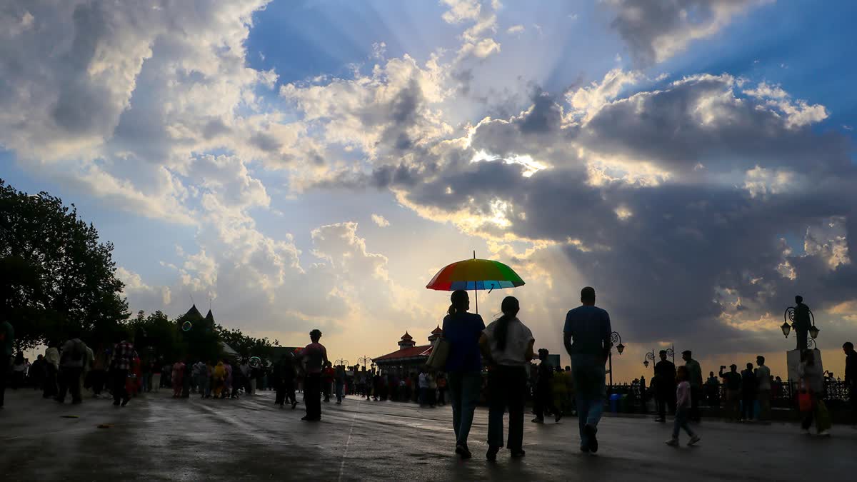 Tourists carrying umbrellas stroll through the Ridge amid cloudy skies and light showers as the pleasant weather brings relief from the scorching heat in the plains in Shimla, Himachal Pradesh on Saturday, May 23, 2026.
