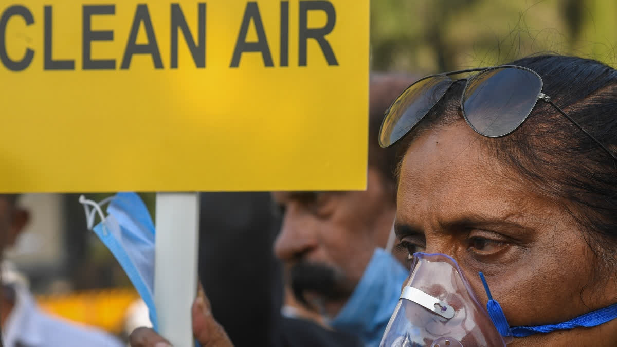 A woman wearing an oxygen mask holds a placard during a protest demanding action against air pollution, in Mumbai, Sunday, Nov. 30, 2025.