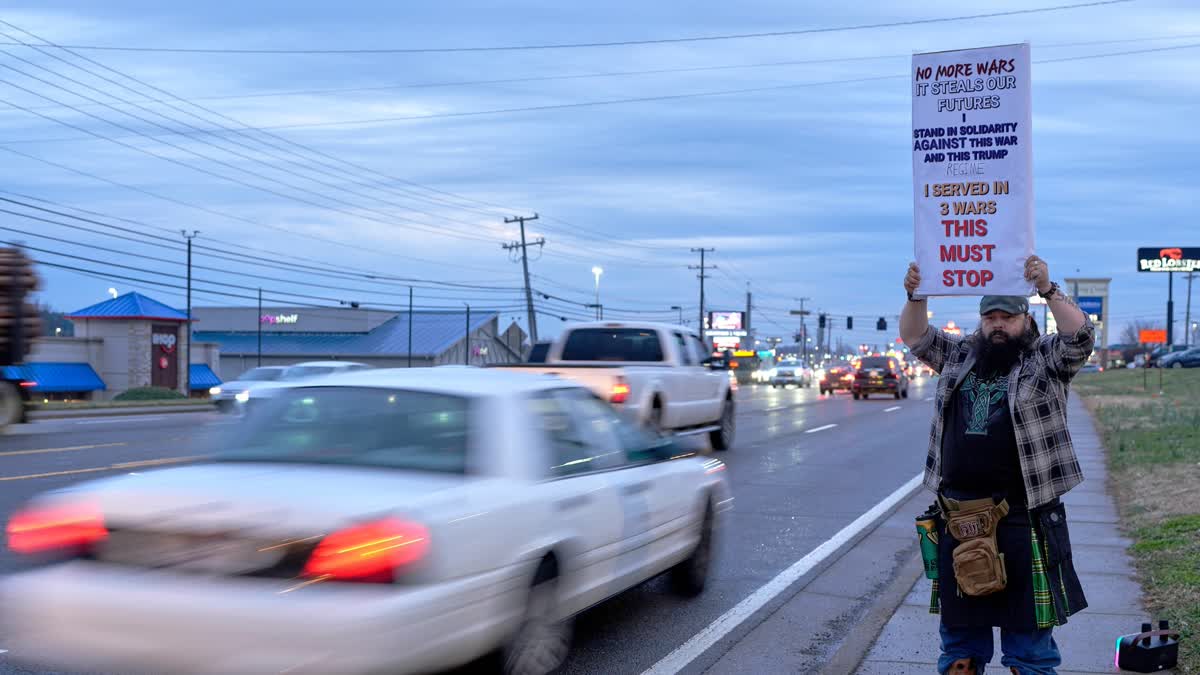 போரை நிறுத்தும்படி அமெரிக்காவிற்கு எதிராக பதாகை ஏந்தியிருக்கும் நபர்