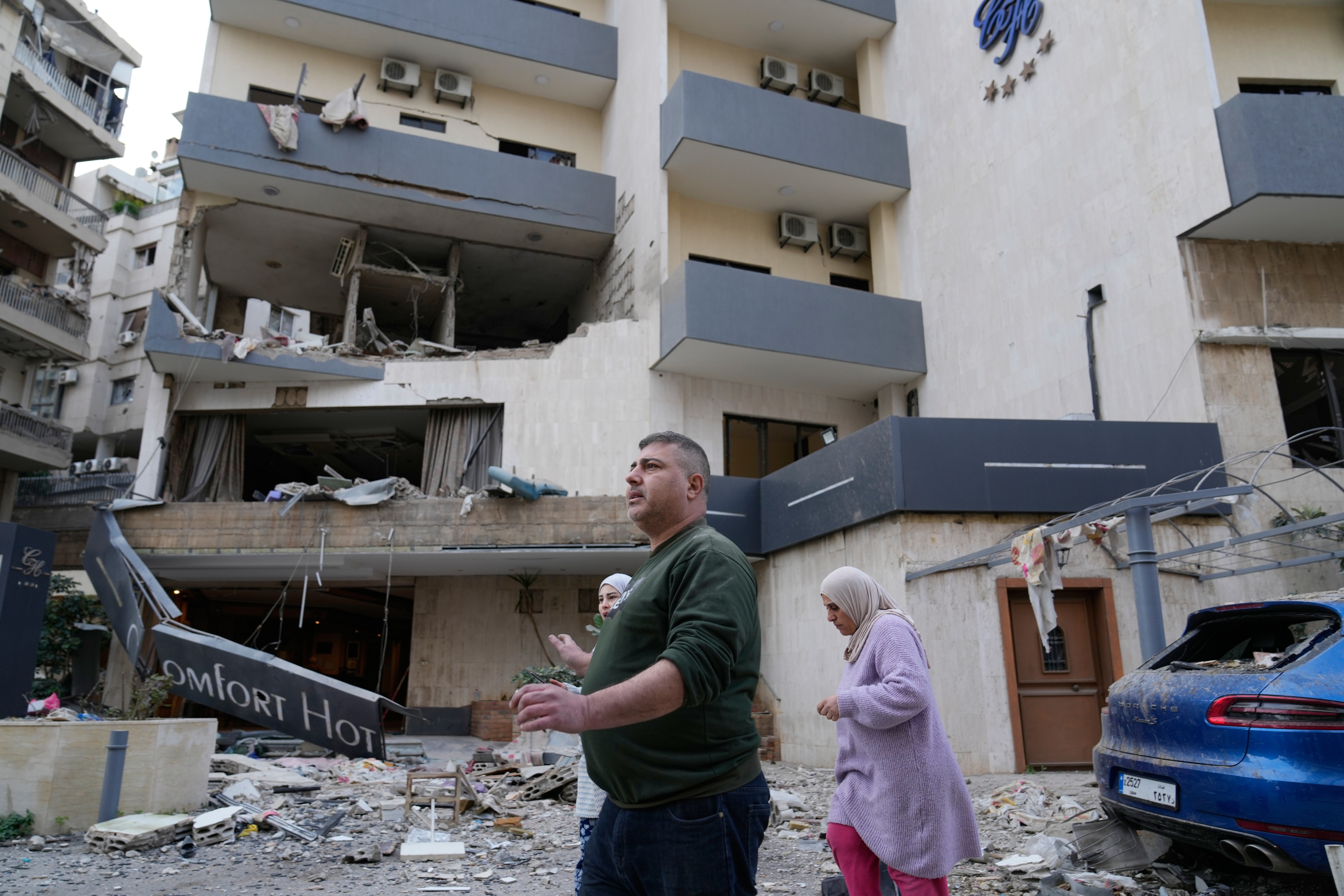 People pass in front of a damaged hotel that was hit by an Israeli airstrike in Hazmieh east of Beirut, Lebanon, Wednesday, March 4, 2026.