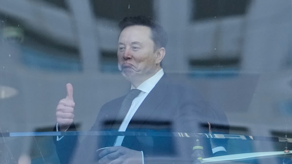 Elon Musk, left, gestures as he walks through a hallway inside the U.S. District Court in Oakland, Calif., Wednesday, April 29, 2026.