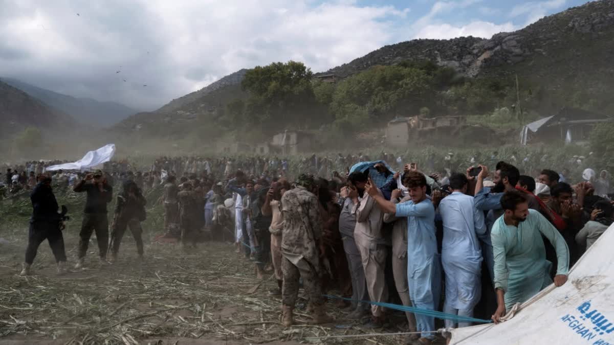 Residents and Taliban soldiers shield themselves from the wind of a helicopter taking off as efforts continue after Sunday night's powerful 6.0-magnitude earthquake that struck several provinces, in Kunar province, eastern Afghanistan, Tuesday, Sept. 2, 2025