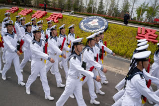 FILE - Sailors march past the insignia for the People's Liberation Army (PLA)'s naval submarine academy during a tour arranged for foreign journalists a day before the opening of the West Pacific