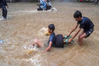 A file photo of Commuters make their way through a waterlogged stretch following heavy rain in western Mumbai.