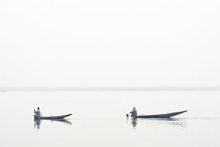 Men steer boats across the Dal Lake on a cold foggy afternoon in Srinagar on December 1, 2025.