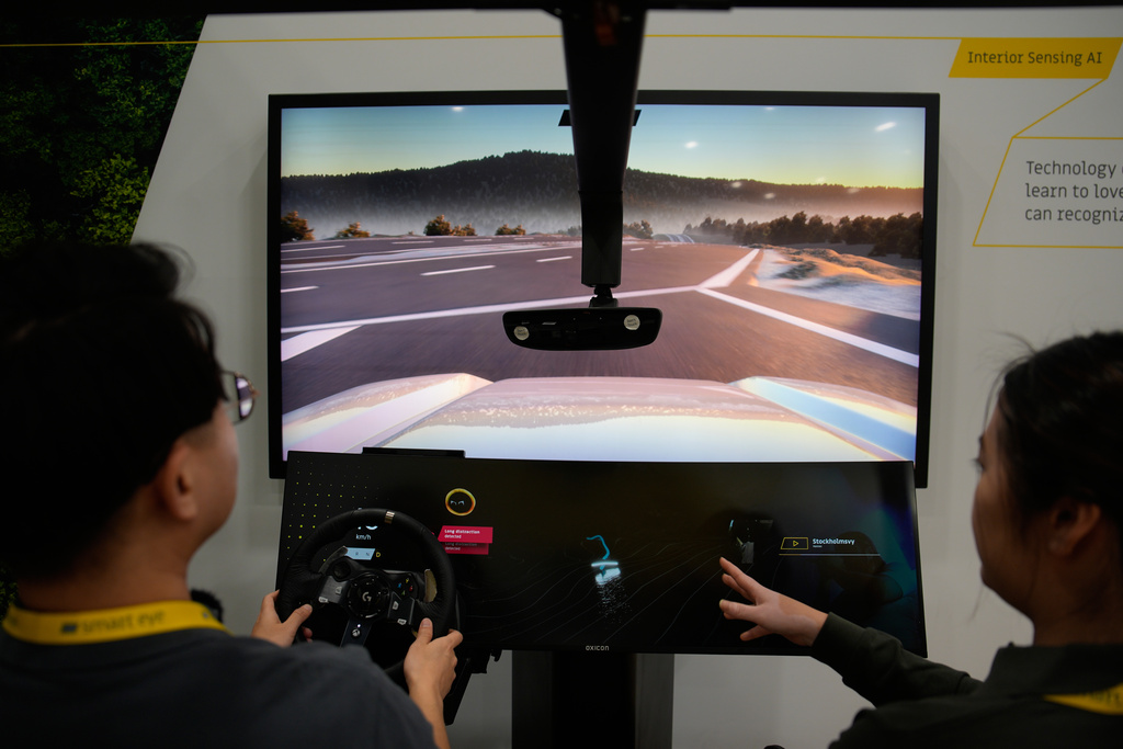 People take part in a simulator for Smart Eye interior sensing AI technology at the Smart Eye booth during the CES tech show Tuesday, Jan. 6, 2026, in Las Vegas