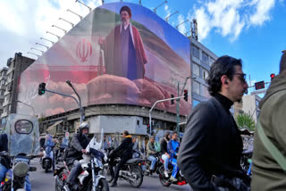 People drive their motorbikes past a billboard that shows a graphic depicting Iran's Supreme Leader Ayatollah Mojtaba Khamenei in downtown Tehran, Iran, Monday, April 6, 2026.