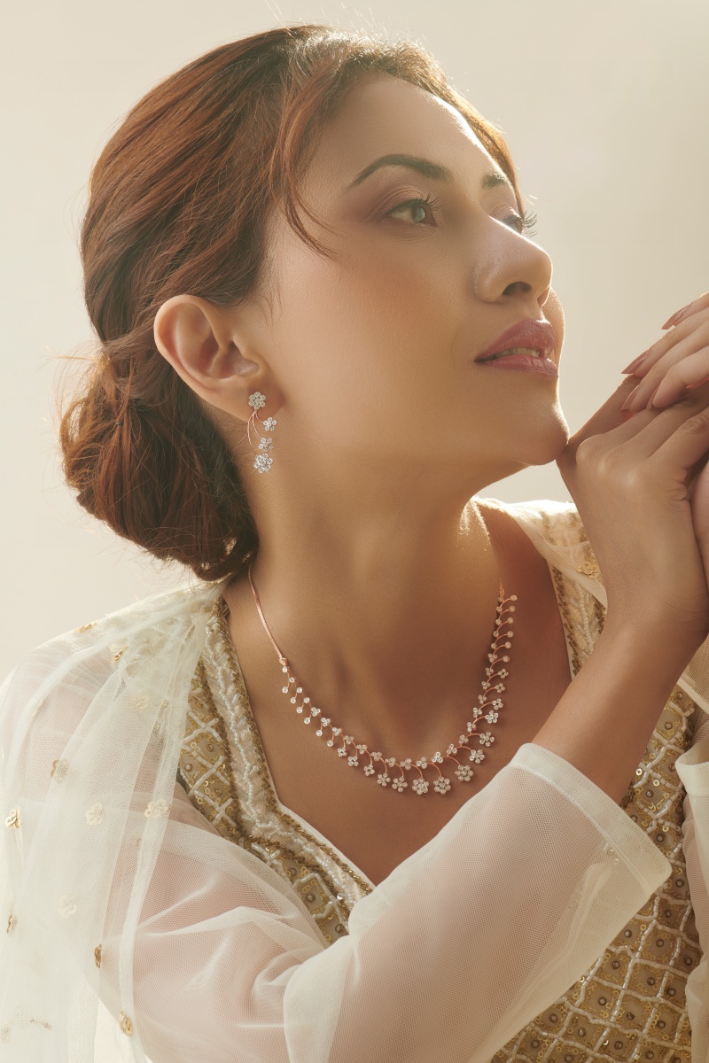 A model wears floral diamond earrings and necklace in rose gold