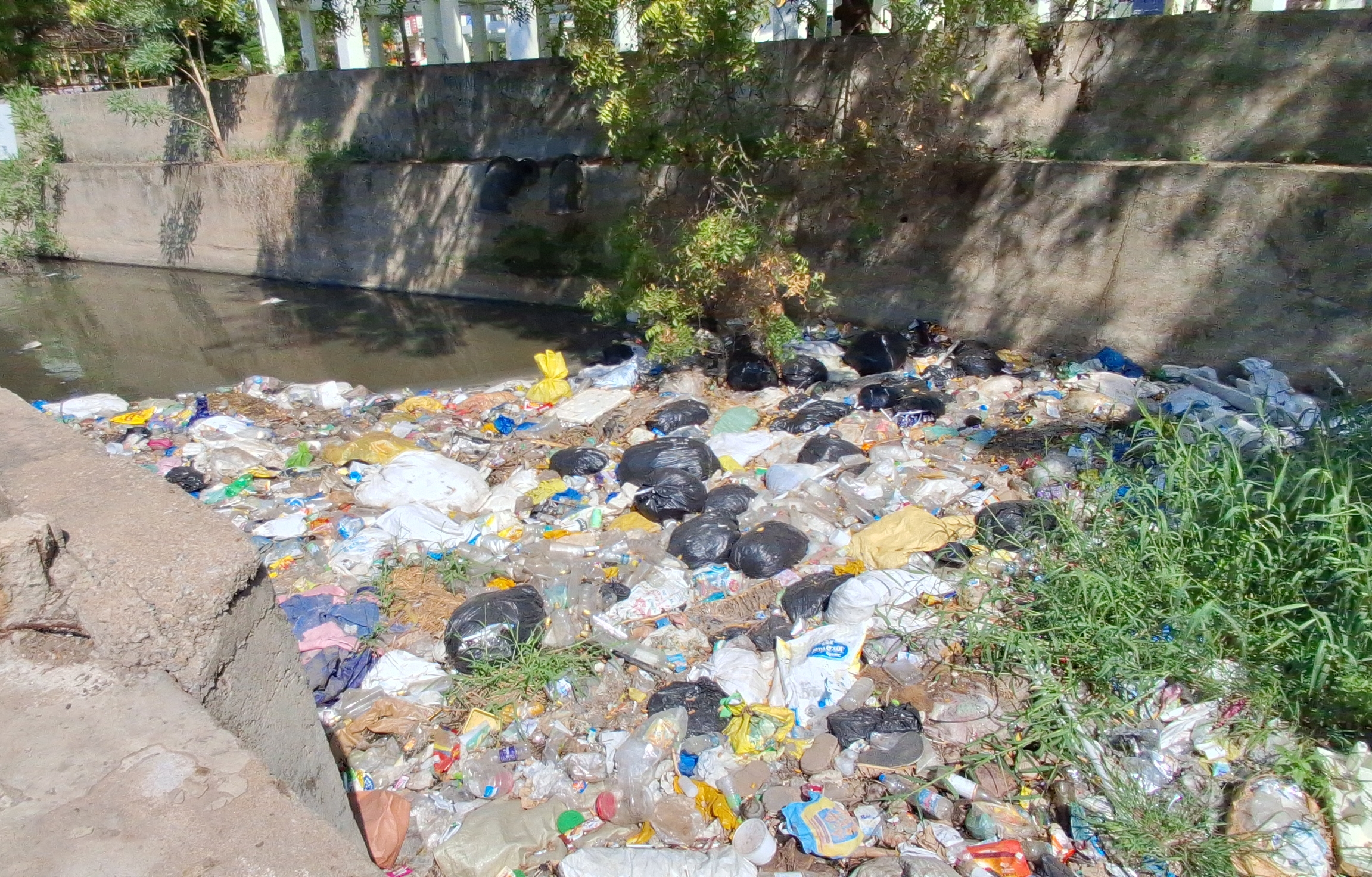 கழிவுநீர் கால்வாயில் குப்பைகளை கொட்டியிருக்கும் மதுரை மாநகர பொதுமக்கள்.