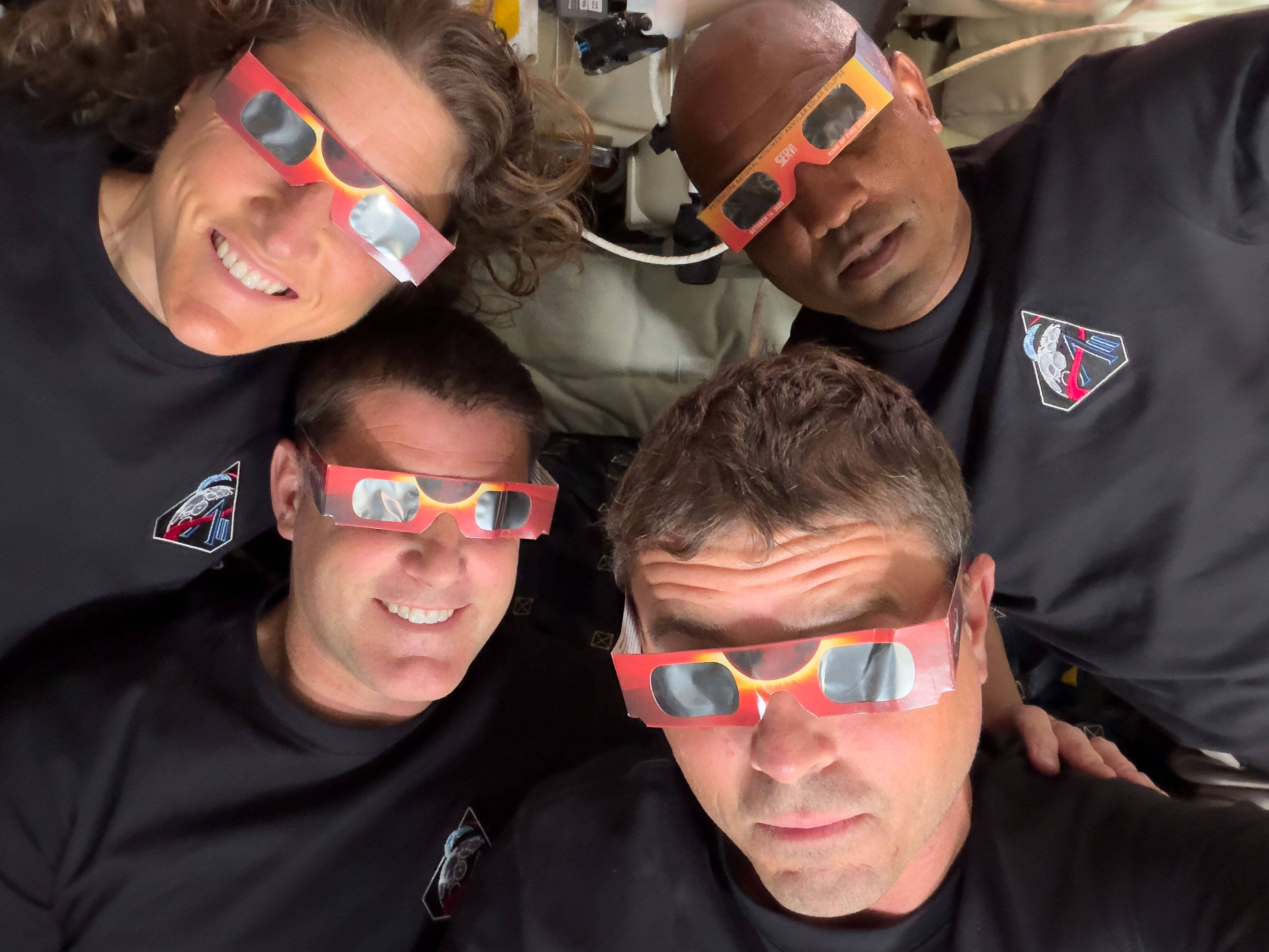 The Artemis II crew, counterclockwise from top left, Mission Specialist Christina Koch, Mission Specialist Jeremy Hansen, Commander Reid Wiseman, and Pilot Victor Glover, pose with eclipse viewers during a lunar flyby