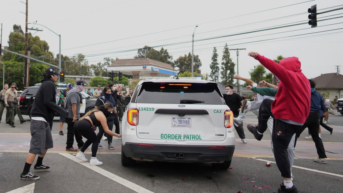 Protesters kick the side of a Border Patrol vehicle during a demonstration over the dozens detained in an operation by federal immigration authorities a day earlier in Paramount section of Los Angeles Saturday, June 7, 2025.