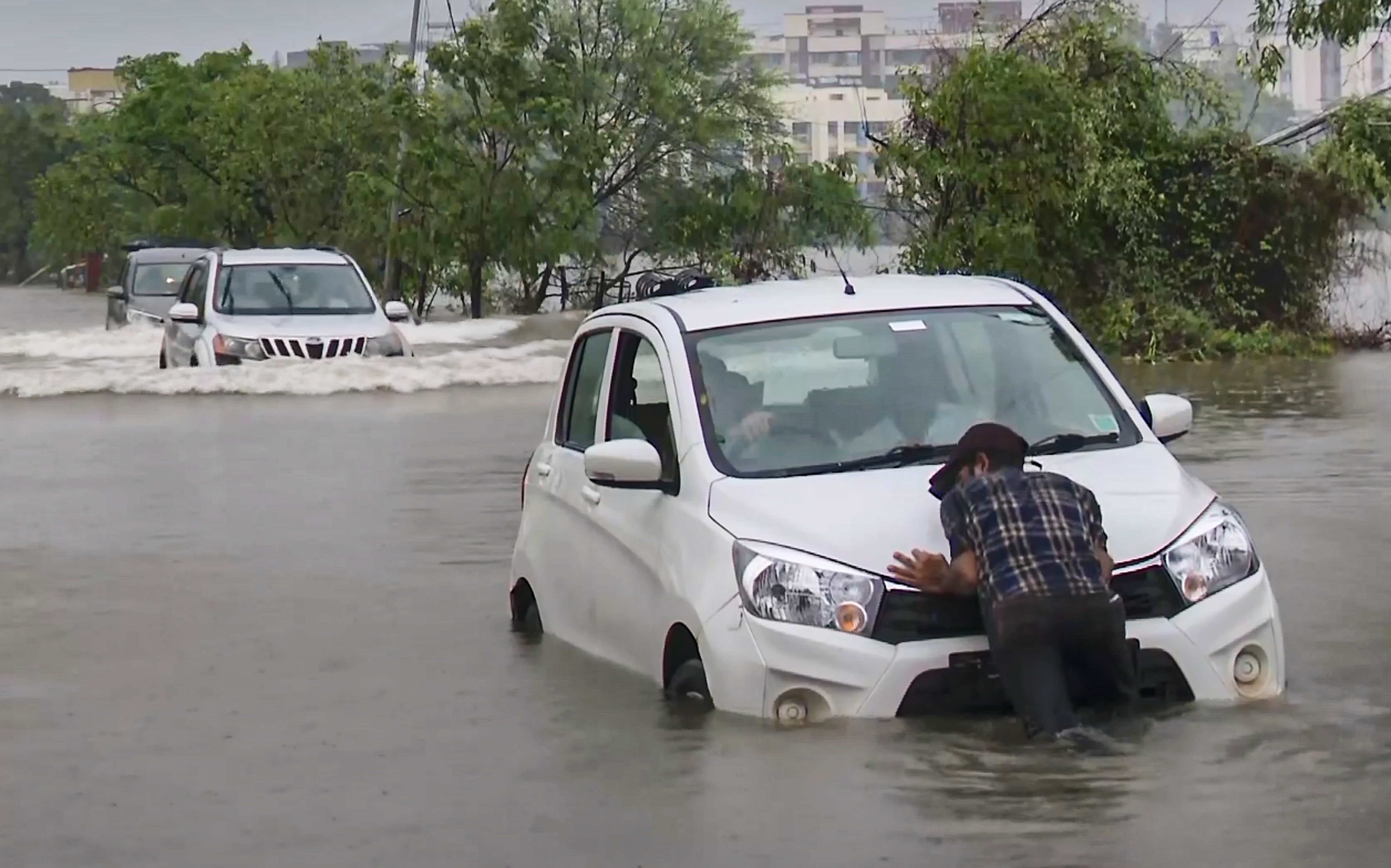A man pushes a stranded car through a waterlogged road as vehicles navigate floodwaters following heavy monsoon rains, in Vasai, Maharashtra, on Wednesday.