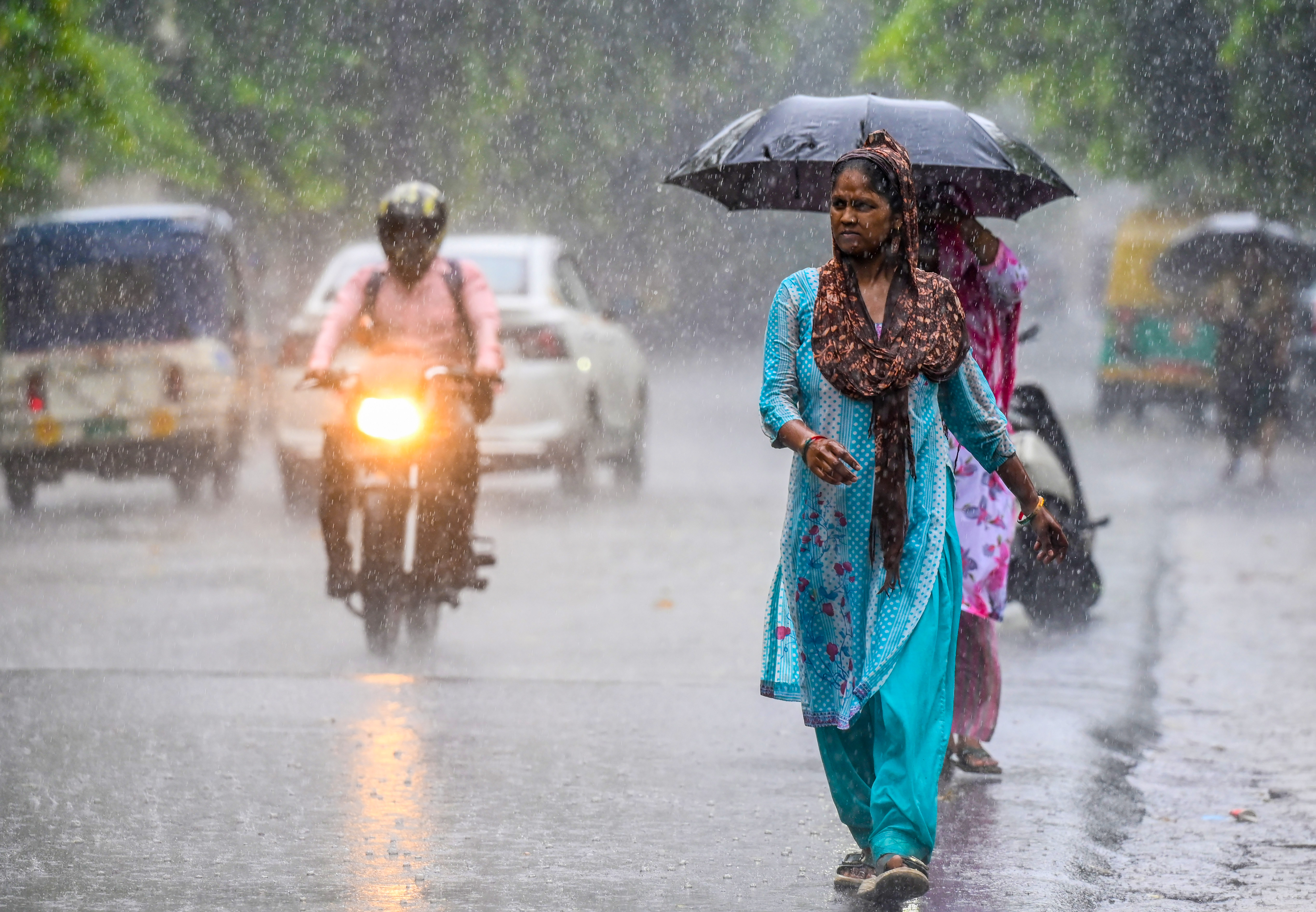 Commuters make their way through a street during rainfall as the monsoon arrives in Noida district of Uttar Pradesh on Wednesday.