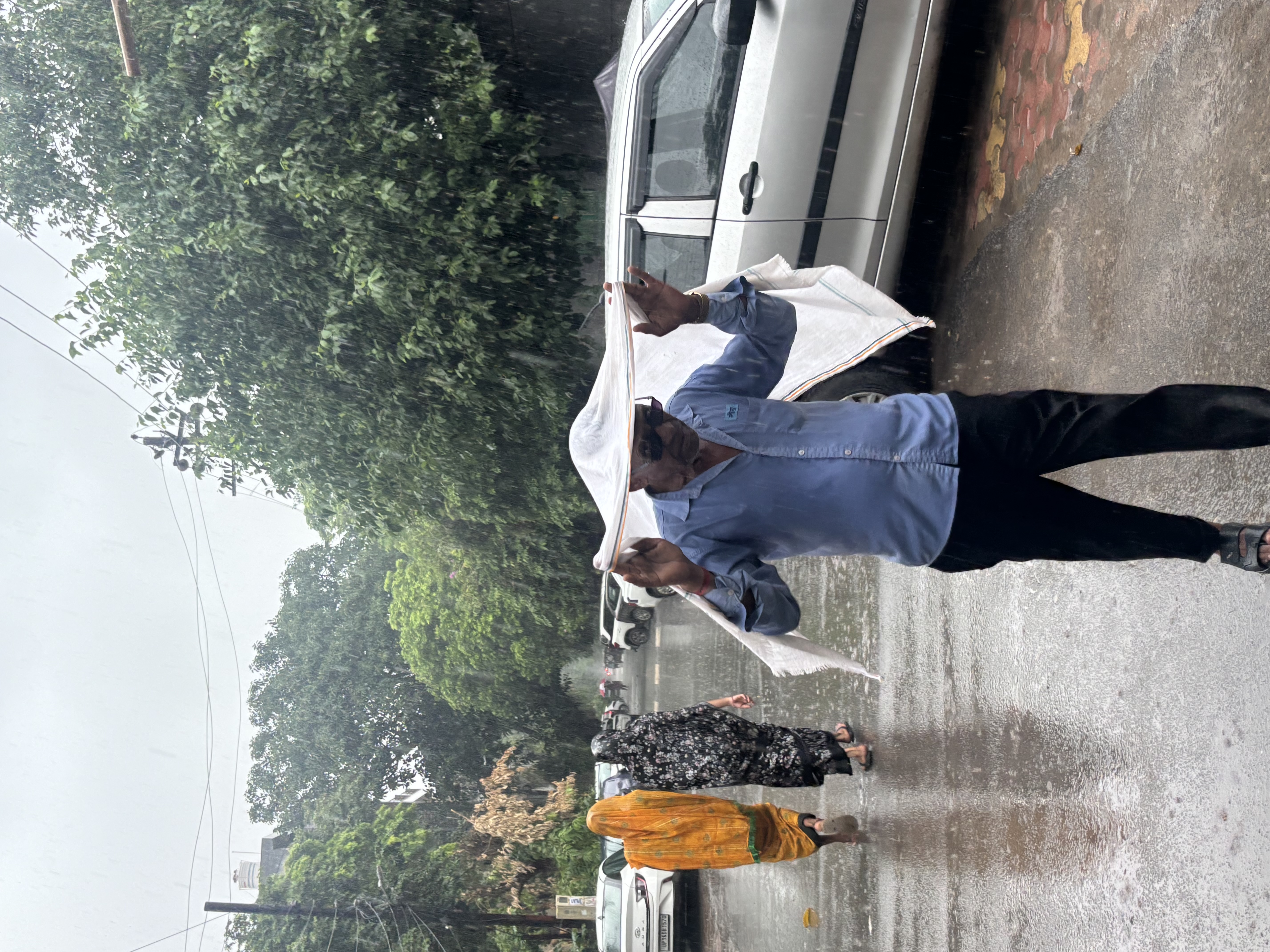 A man covers himself amid rainfall in Noida, on Wednesday.