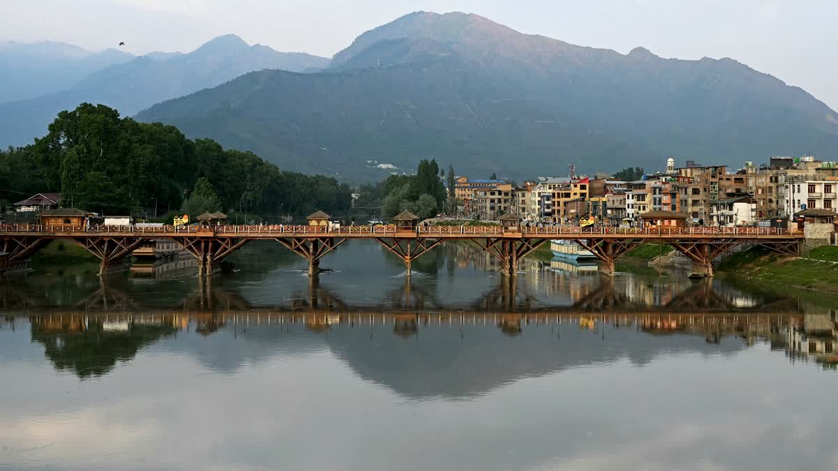 A reflection of a walkover bridge shimmers over Jhelum river in Srinagar on May 10, 2025.