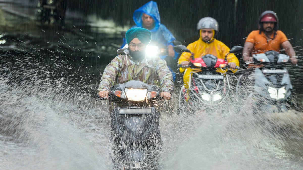 Commuters wade through a severely waterlogged underpass during heavy rainfall, at Jangpura, in New Delhi, on Thursday.