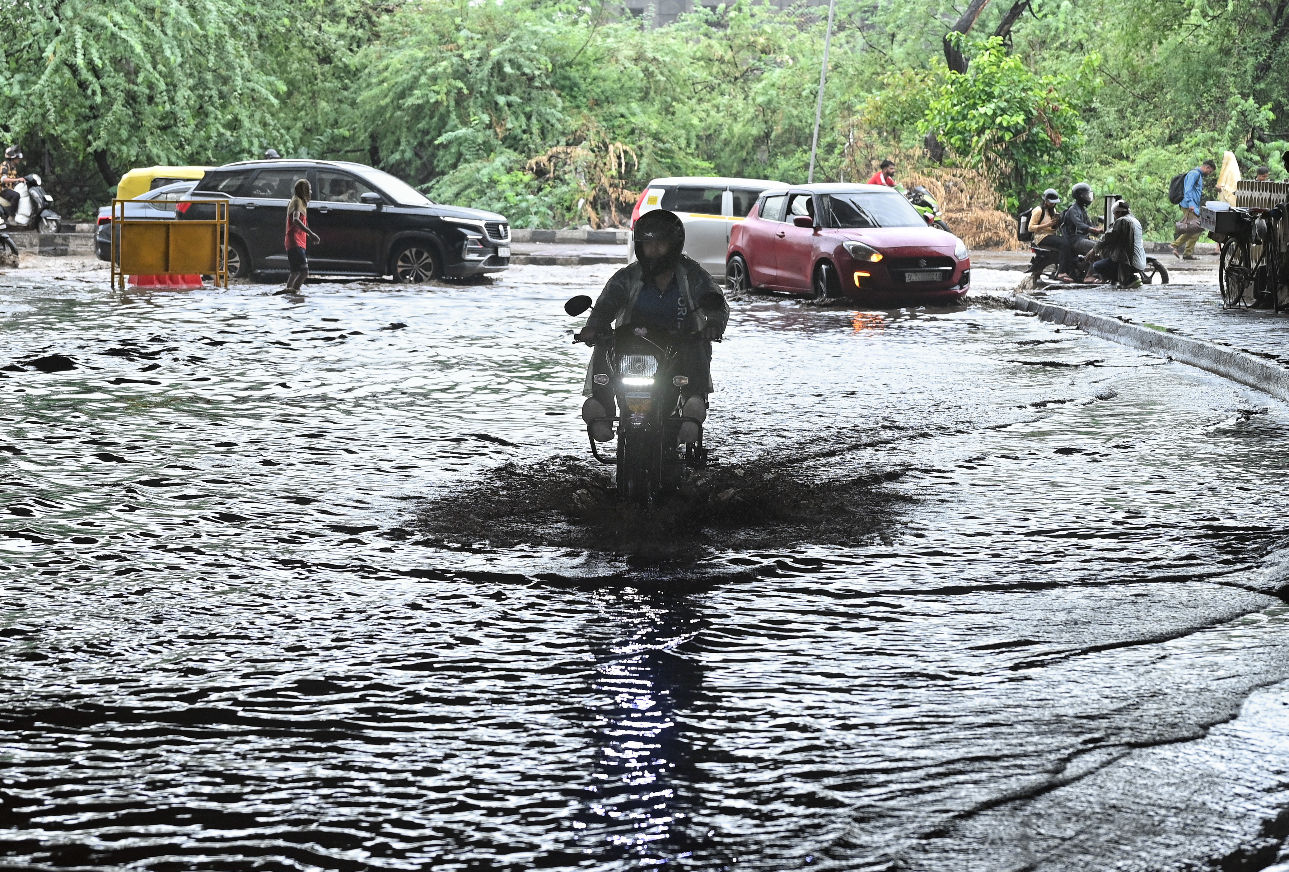 Commuters make their way through a waterlogged area amid rain at Gazipur, in New Delhi.