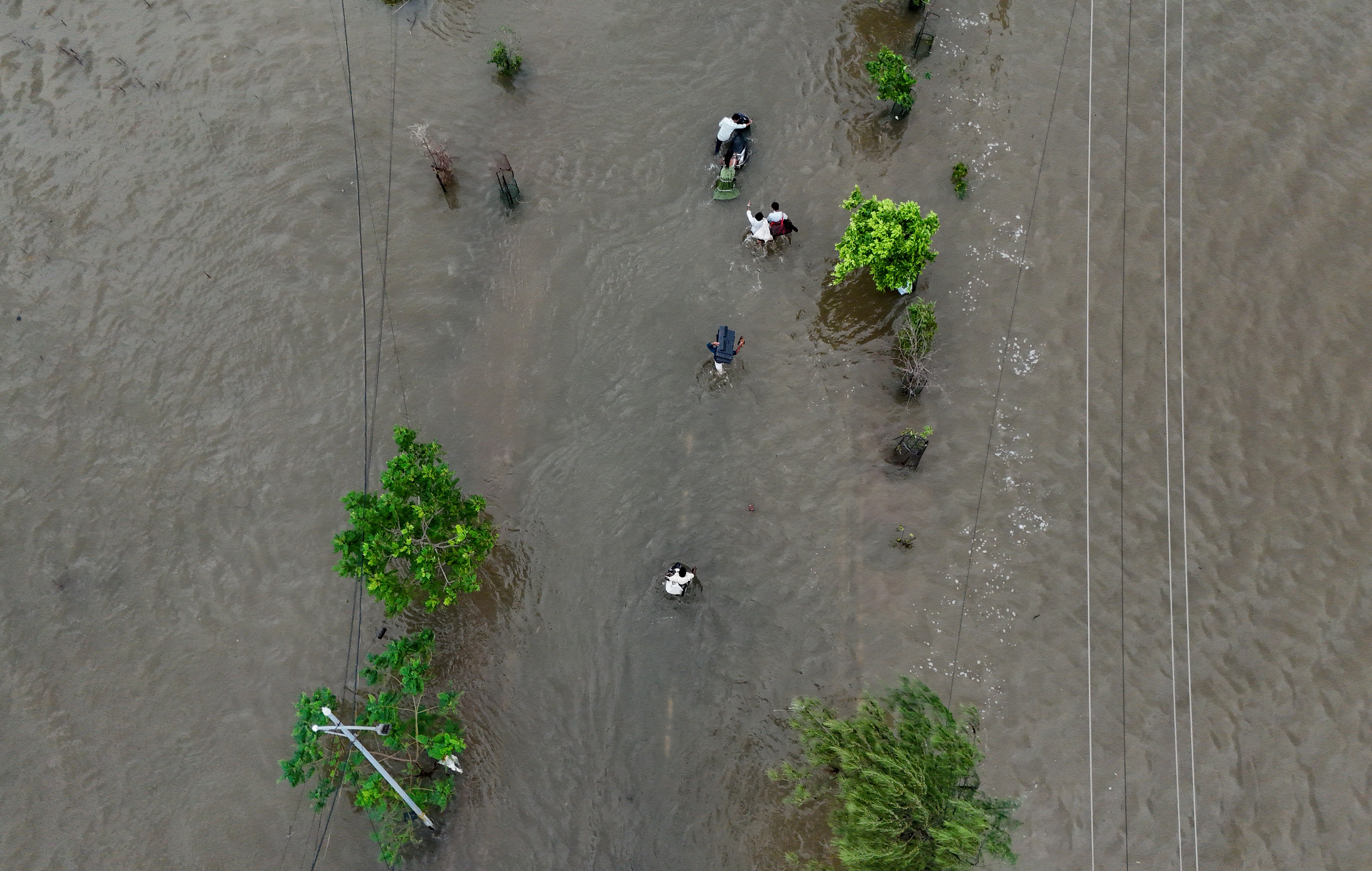 Commuters navigate a waterlogged road after heavy rainfall, at Vasai-Virar in Palghar district, Maharashtra.