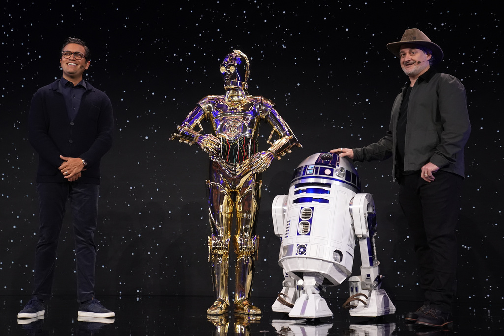 Asad Ayaz, left, and Dave Filioni stand on stage with C-3PO and R2-D2 during an LEGO news conference ahead of the CES tech show Monday, Jan. 5, 2026, in Las Vegas.