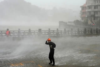 man walks against strong wind and rain as Typhoon Dolphin