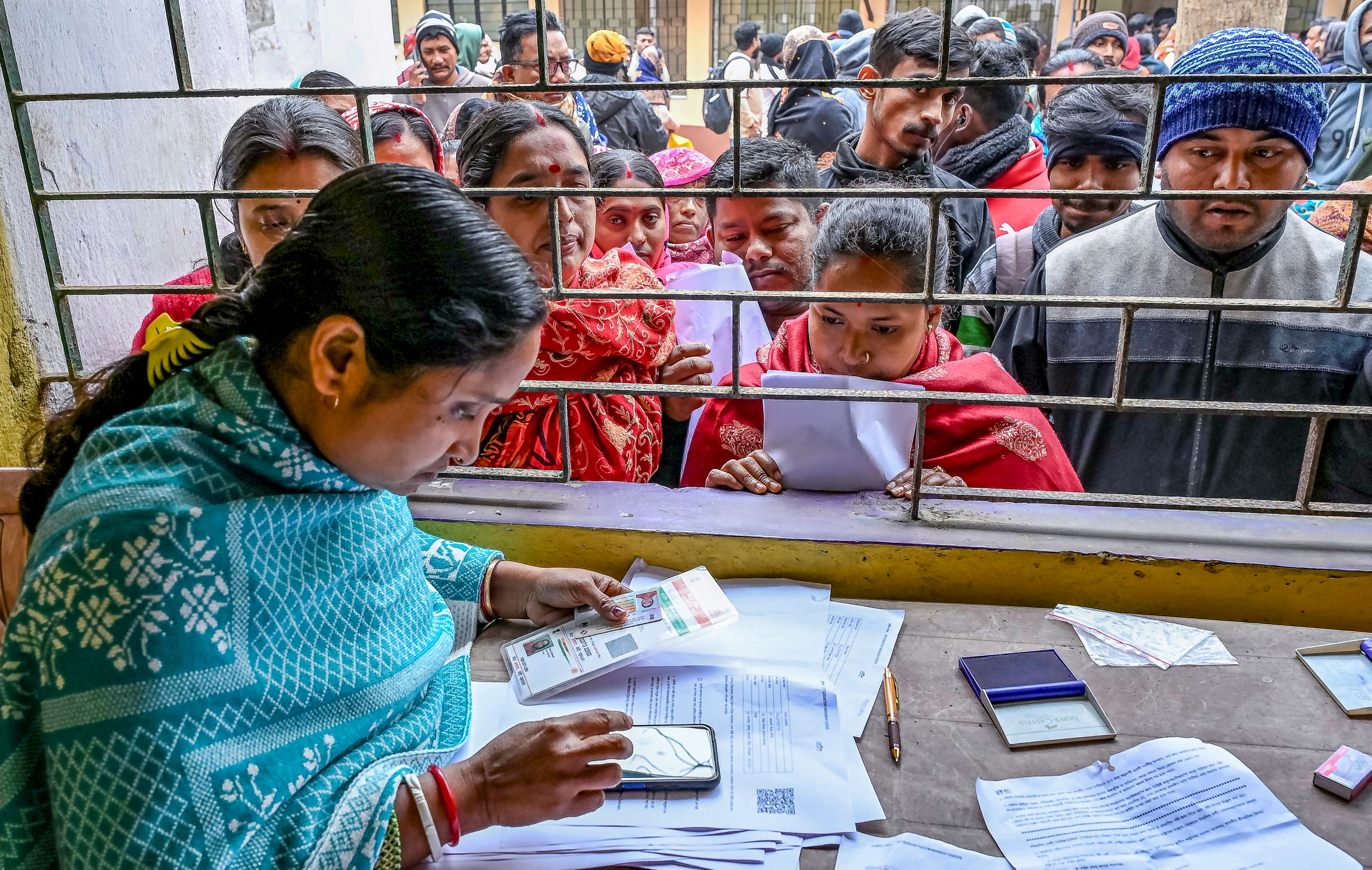 સોમવાર, 5 જાન્યુઆરી, 2026ના રોજ પશ્ચિમ બંગાળના નાદિયામાં મતદાર યાદીના વિશેષ સઘન સુધારણા (SIR) હેઠળ સુનાવણી દરમિયાન લોકો એક સેન્ટર પર રાહ જોઇ રહ્યા છે.