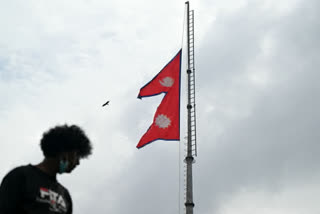 FILE - A man walks past as Nepal's national flag flies at half-mast in Kathmandu