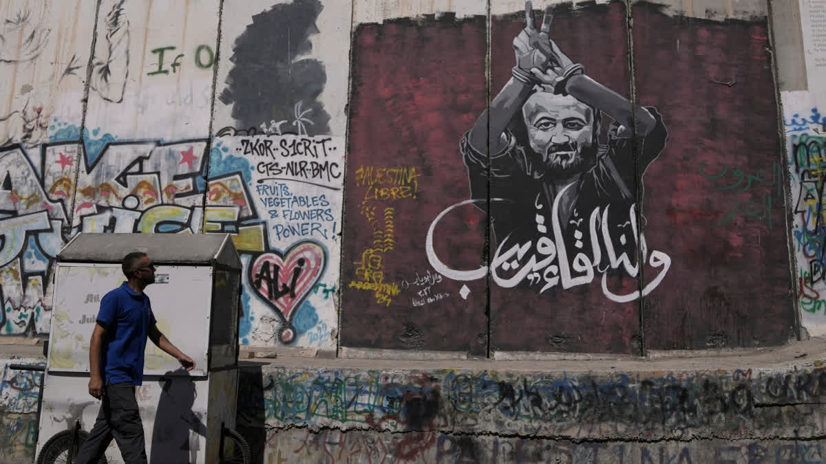 FILE - A man walks past a mural depicting the Palestinian leader Marwan Barghouti, with a message that reads in Arabic, "See you soon,” on Israel's separation barrier in the West Bank city of Bethlehem, Aug. 20, 2025.