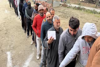 Voters queue up outside a polling station to cast vote during bypoll to Budgam assembly seat