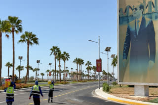 Workers carry paint as they walk past a banner showing Egyptian President Abdel-Fattah el-Sissi at the Red Sea city of Sharm el-Sheikh, Egypt, Saturday, Oct. 11, 2025, where President Donald Trump is expected to hold a summit of world leaders on Gaza during his visit.