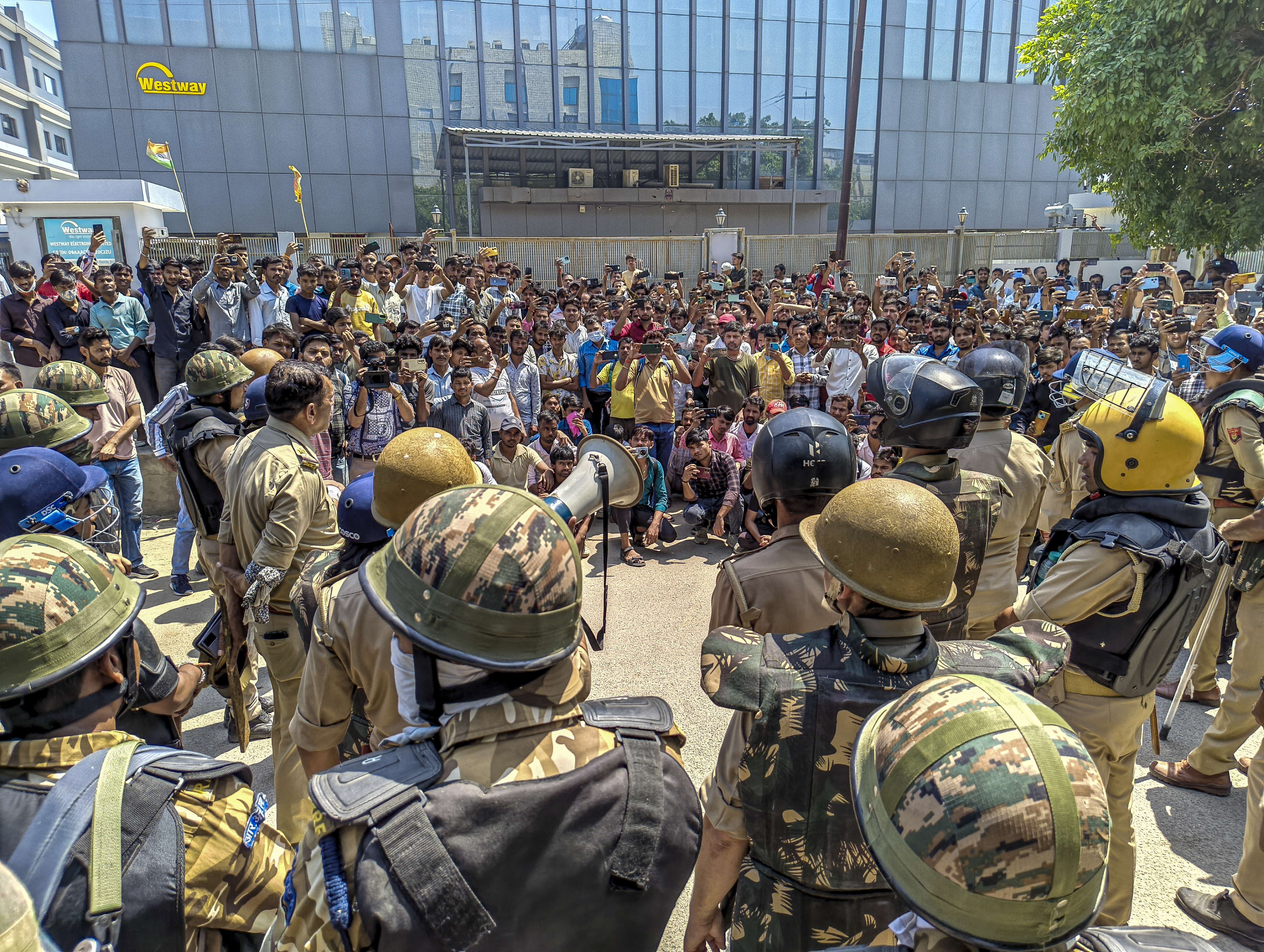 Security personnel stand guard as factory workers stage a protest in Noida.