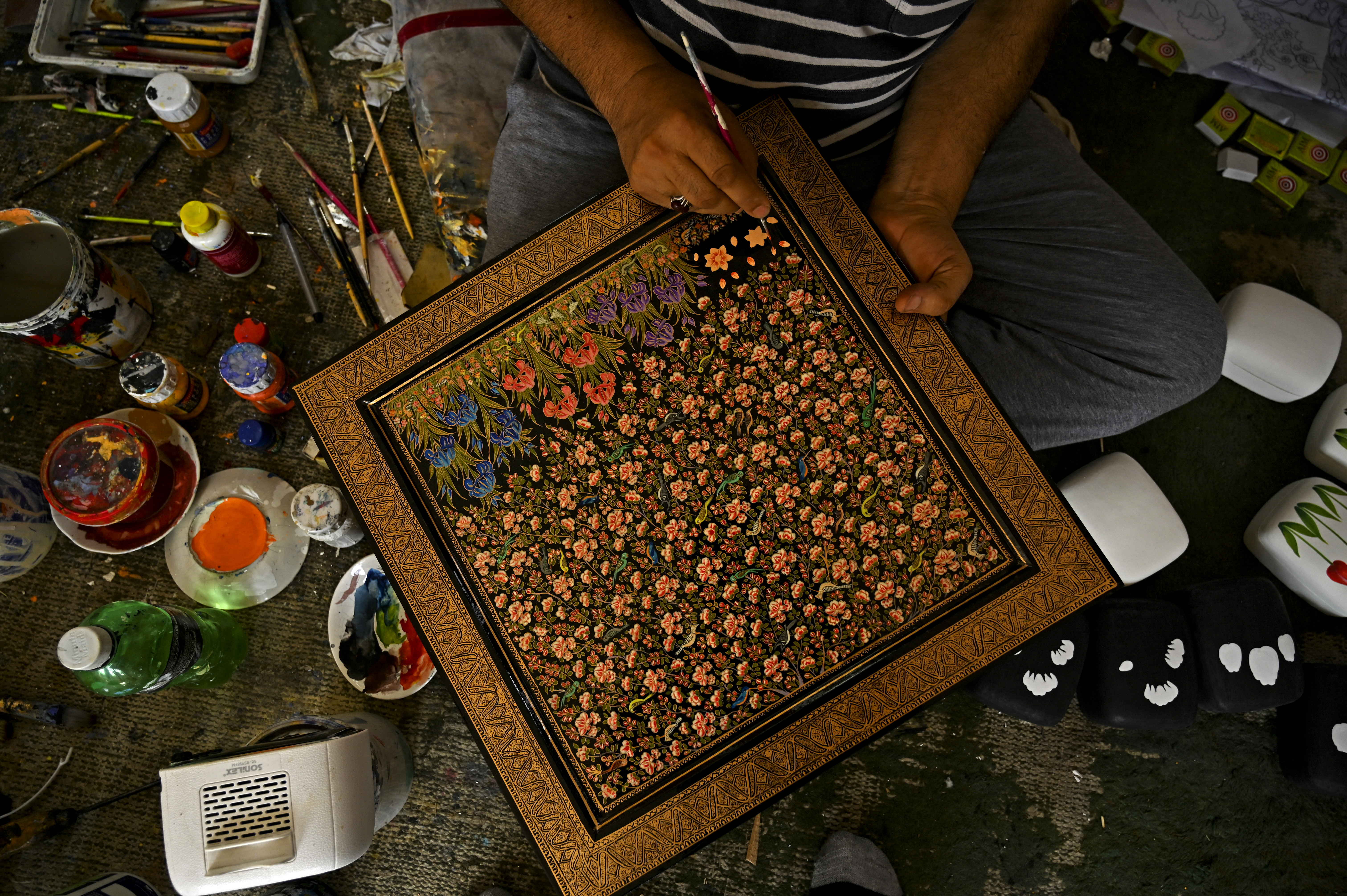 A Kashmiri artisan paints the finishing touches of a papier-mâché craft in Srinagar