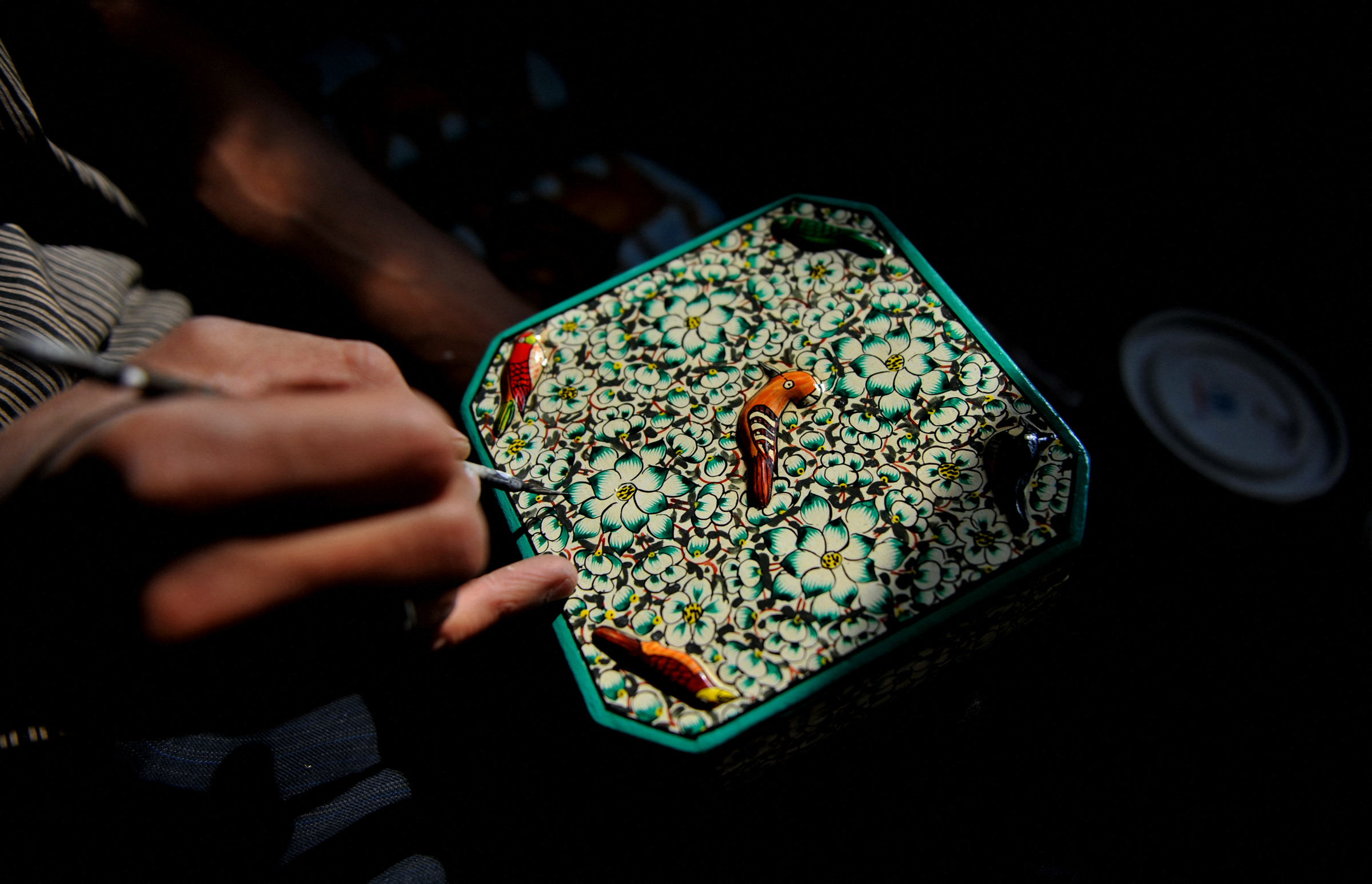 A Kashmiri Muslim artisan gives the final touches to a papier mache product before sending it to the market on the outskirts of Srinagar