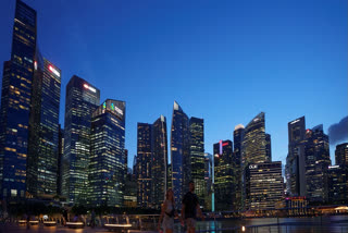FILE - Tourists walk in front of the Central Business District during sunset in Singapore, on May 30, 2024.